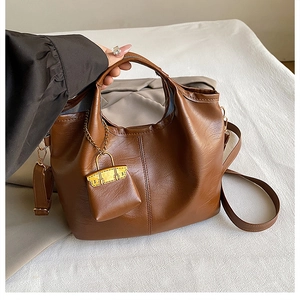 Vue détaillée du sac seau en cuir marron foncé avec chaîne dorée et petite pochette ronde