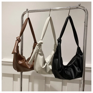 Dettaglio di tre borse hobo morbide in marrone beige e nero con spalline annodate