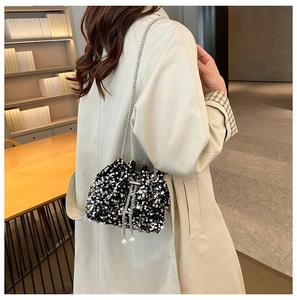 Detail of sequin bucket bag with silver chain strap and pearl drawstring closure