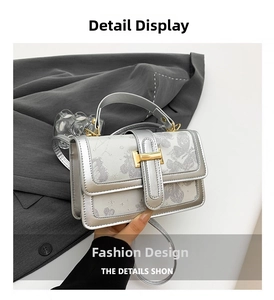 Macro detail of silver shoulder bag showing gold H-clasp and delicate floral star pattern