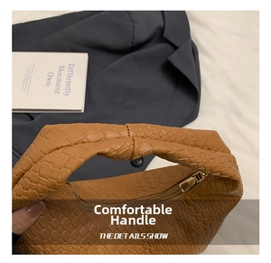 Detail of woven leather texture and metal zipper on a caramel brown tote bag