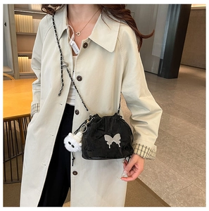 Fashionable black drawstring bucket bag with silver butterfly and white plush charm on model