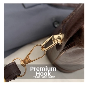 Macro shot of premium light gold lobster clasp hardware and brown leather stitching