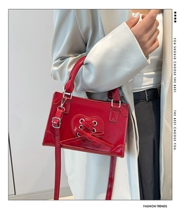 Detail of red leather bag featuring heart lace-up design and silver metal hardware