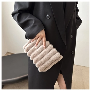 Détail de la texture d'un sac à main en peluche rayé porté par un mannequin chic