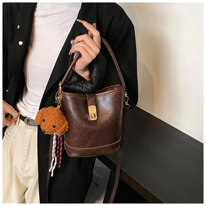 Detail of dark brown vintage bucket bag with textured faux leather and gold buckle closure