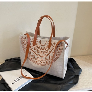 Detail of bohemian canvas tote bag with brown geometric sun pattern and leather handles