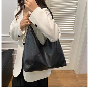 Detail of minimalist black leather tote bag featuring unique diagonal stitching patterns