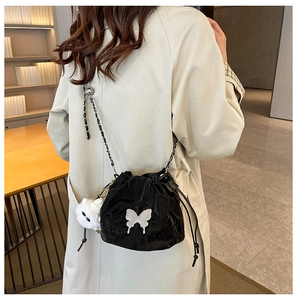 Detail of black drawstring bucket bag with butterfly patch and plush bear charm