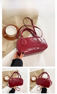 Detail showing red glossy leather Boston bag with double top handles and sleek stitching