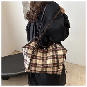 Detailed close-up of the vintage plaid canvas tote bag with brown leather handles and logo