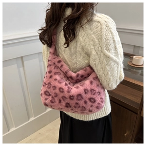 Détail du sac à bandoulière en peluche léopard rose avec un pull en maille blanc