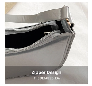 Detail of a metallic silver underarm bag showing the secure gold zipper closure