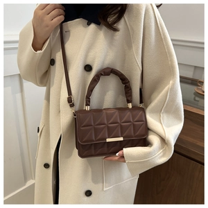 Close-up of brown quilted crossbody bag with gold metal lock and ruched handle