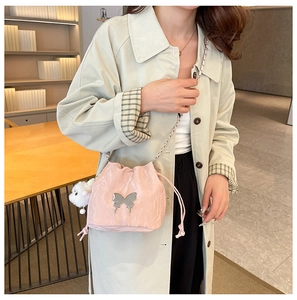 Detailed shot of pink drawstring bucket bag with silver butterfly and plush pom charm