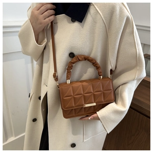 Detail of a brown geometric quilted handbag with gold clasp and pleated handle