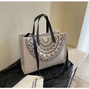 Detail of beige canvas tote bag with black sunburst pattern on leather background