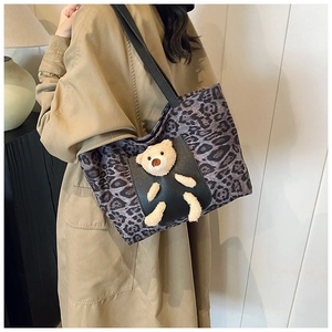 Detailed view of leopard print tote bag featuring a cute 3D plush bear on black front pocket
