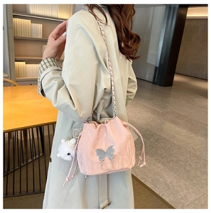 Detail of pink drawstring bucket bag with silver butterfly and plush charm accessory