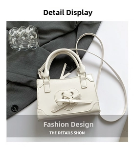 Close-up of white PU leather square handbag with heart lace bow and adjustable strap