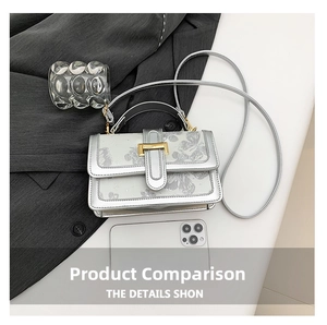 Detail of silver crossbody bag with butterfly prints next to a phone for size comparison