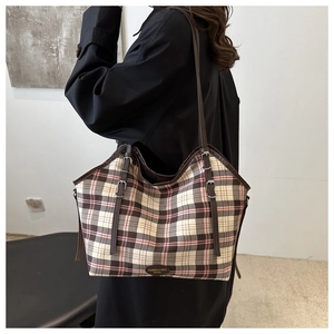 Detail of vintage plaid canvas tote bag with leather trim and decorative straps