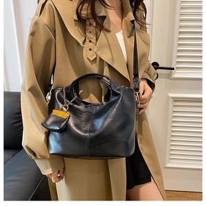 Retro black glossy leather tote bag with small pouch shown on model in khaki trench coat