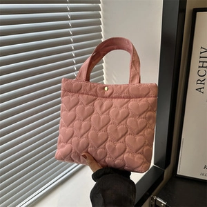 Detail einer rosa gesteppten Herz-Handtasche mit goldener Drucktaste und Stoffstruktur