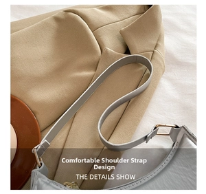 Detail of grey leather crescent bag featuring adjustable strap and gold metal buckle