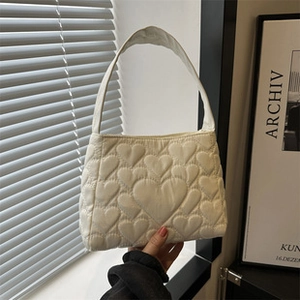 Detailansicht der beigen Stepptasche mit Herzmuster-Stickerei und einzelnem Tragegriff