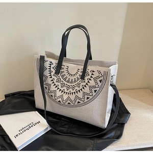 Detail of canvas tote bag with ethnic geometric pattern on black leather apparel