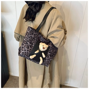 Detail of grey leopard print tote bag with plush bear pocket worn over khaki coat