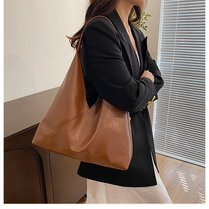 Brown large capacity leather shoulder bag shown in a minimalist interior setting
