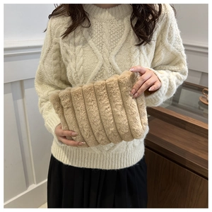 Détail d'un sac à main en peluche beige à rayures verticales tenu par un mannequin