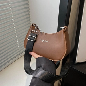 Detail einer braunen Halbmondtasche mit Fashion-Logo und breitem schwarzem Nylon-Schultergurt