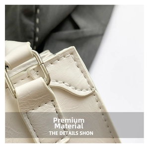 Detail of white leather shoulder bag showing precision stitching and silver metal hardware