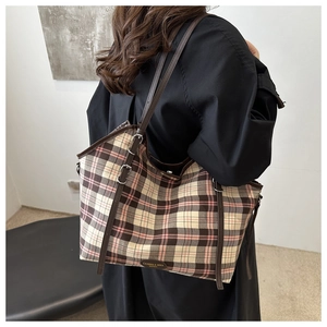 Detail of pink and brown plaid tote bag featuring high-quality leather straps and buckles