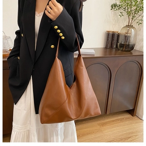 Brown leather tote bag with unique triangular profile and diagonal stitching detail