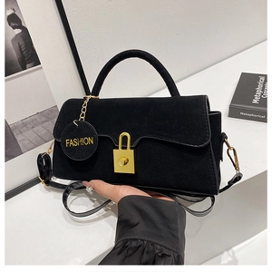 Dettaglio borsa a mano in pelle scamosciata nera con chiusura dorata e ciondolo moda