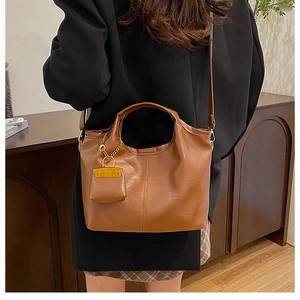 Détail d'un sac seau marron montrant la texture du cuir fin et les coutures verticales