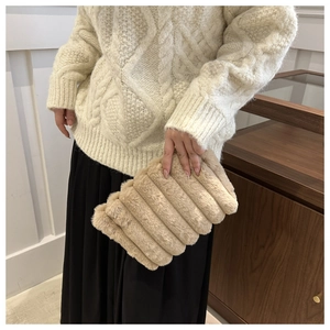 Detail of beige faux fur clutch with vertical stripes and fluffy winter texture