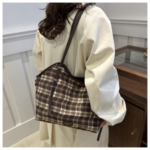 Detail of vintage brown checkered canvas tote bag with leather strap and metal logo