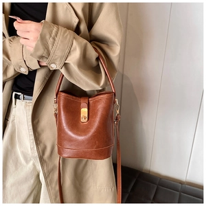 Macro shot of brown vintage bucket bag texture and gold buckle on a crossbody strap