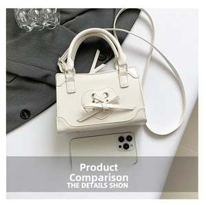 Detail view of mini white PU leather handbag with heart cutout and ribbon bow design