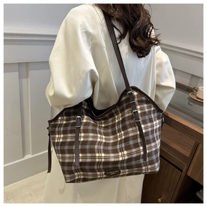 Detail of adjustable leather strap and brown checkered pattern on a large canvas tote bag
