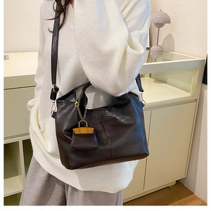 Détail d'un sac seau vintage marron foncé avec un petit pendentif orange sur le devant