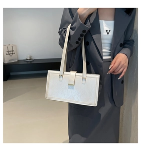 Minimalistische weiße Ledertasche mit Faltenstruktur und Goldbeschlägen am Modell