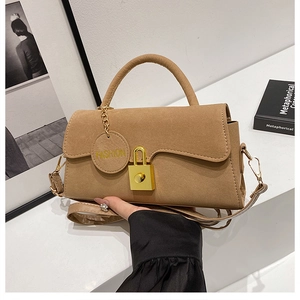 Dettaglio borsa a mano in pelle scamosciata color cammello con chiusura girevole dorata