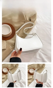 Close-up of white faux leather underarm bag with gold hardware and fine texture