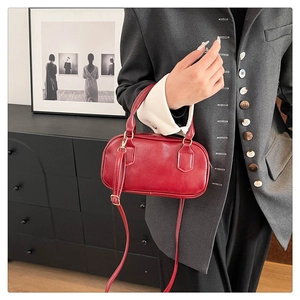 Detail of deep red Boston bag with fine leather texture and golden metal hardware